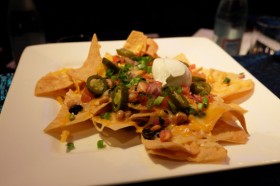 Tortilla chips piled high, layered with a three bean mix, Monterey Jack, cheddar cheeses, freshly made pico de gallo, jalapenos, green onions and sour cream is named the ‘Nachopalooza’