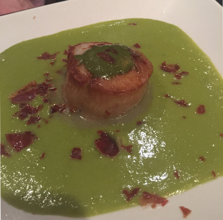 Scallop with pesto and pea puree and bacon pieces