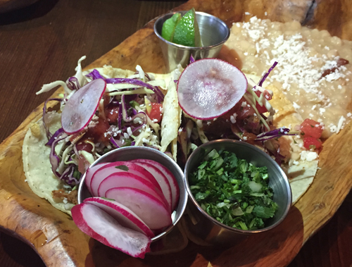 Lamb tacos are braised in beer and topped with cabbage slaw and watermelon salsa.