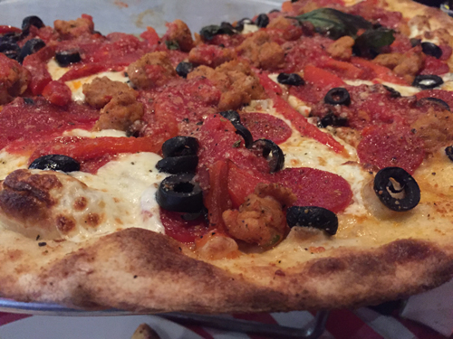 Pizza with spicy chicken sausage, pepperoni, olives and roasted red pepper.