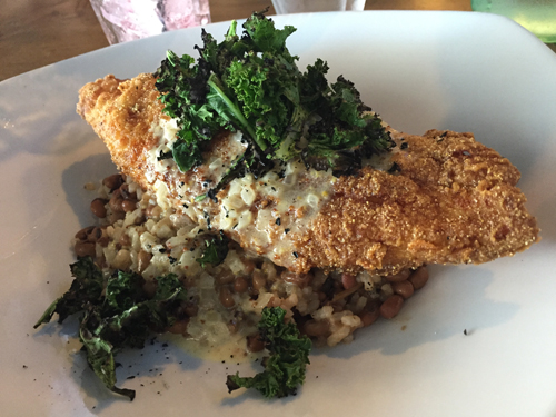 Southern fried catfish draped over gold rice and red peas and topped with charred greens