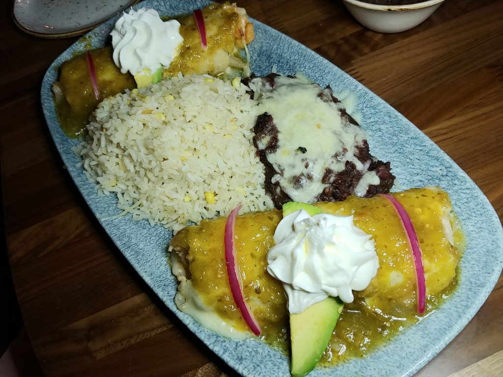 Shrimp and Crab Enchiladas baked with roasted tomatillo salsa, avocado, and sour cream